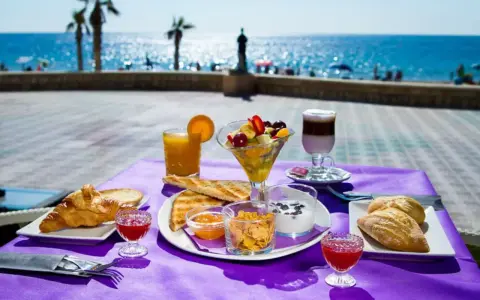 Desayuno frente al mar en Calpe: cruasanes, tostadas, fruta fresca, yogur y café. ¡Un lugar ideal donde comer en Calpe!
