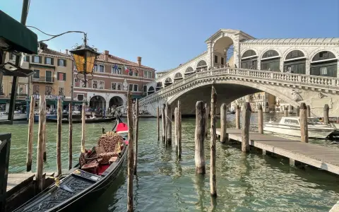 Góndola esperando en el canal, con el Puente de Rialto al fondo. Ideas para que ver en Venecia en dos días.