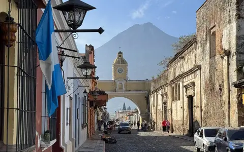 Calle empedrada en Antigua Guatemala, con el arco de Santa Catalina y el volcán de Agua al fondo. Ideal para descubrir qué ver en Antigua Guatemala.