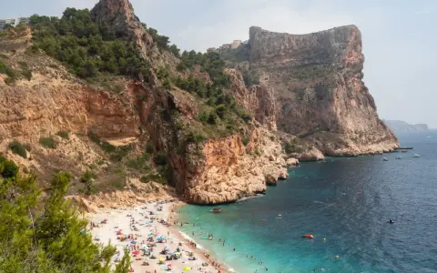 Playa con acantilados y gente disfrutando del sol y el mar. Un plan perfecto para saber qué ver en Alicante provincia en una semana.