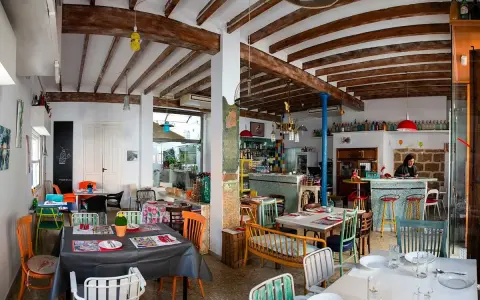 Un restaurante acogedor en Dénia, con mesas coloridas y vigas de madera. Ideal para saber donde comer en Dénia.