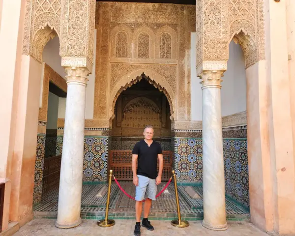 Hombre posa ante intrincada arquitectura marroquí. ¡Ideas para que ver en Marrakech en 2 días!