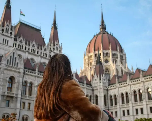 Mujer con abrigo de pelo admira el Parlamento de Budapest, un destino ideal donde viajar en noviembre en Europa.