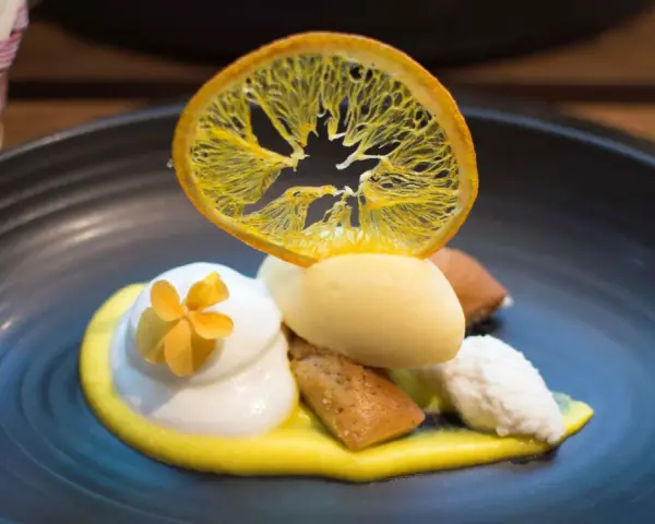 Postre de autor con helado de limón, merengue, bizcocho y naranja deshidratada. ¡Una delicia para saber dónde comer en Barcelona!