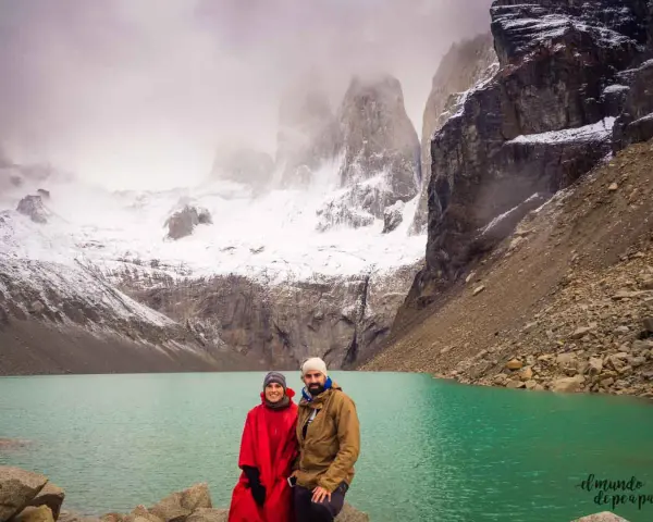 Pareja posa frente a un lago turquesa y montañas nevadas, un paisaje imperdible que ver en Chile.