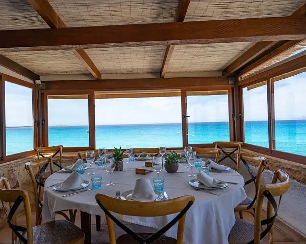 Mesa puesta con vistas al mar turquesa, ideal para saber donde comer en Formentera.