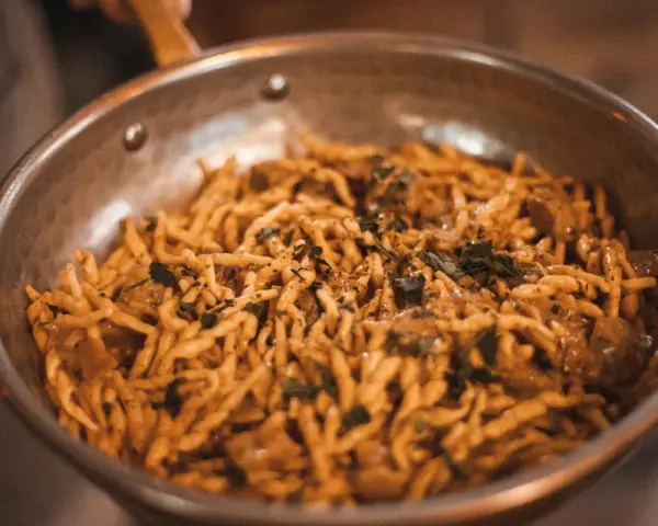Pasta con salsa cremosa y hierbas en sartén. ¡Una deliciosa opción para saber dónde comer en Madrid!
