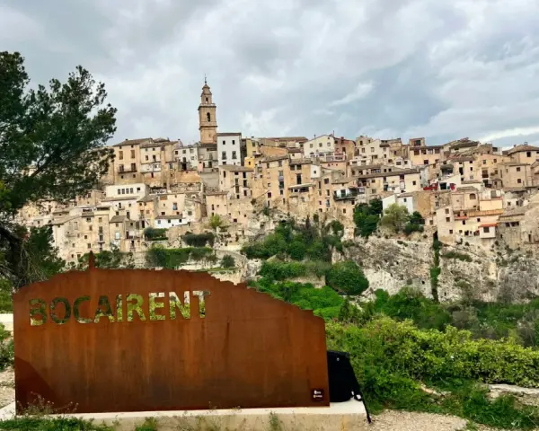 Cartel de "Bocairent" con el pueblo al fondo. Descubre qué ver en Bocairent, un pueblo colgado en la roca.