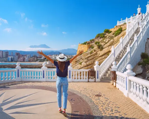 Mujer con brazos abiertos admira la vista de Benidorm desde el mirador. ¡Un lugar ideal que ver en Benidorm!