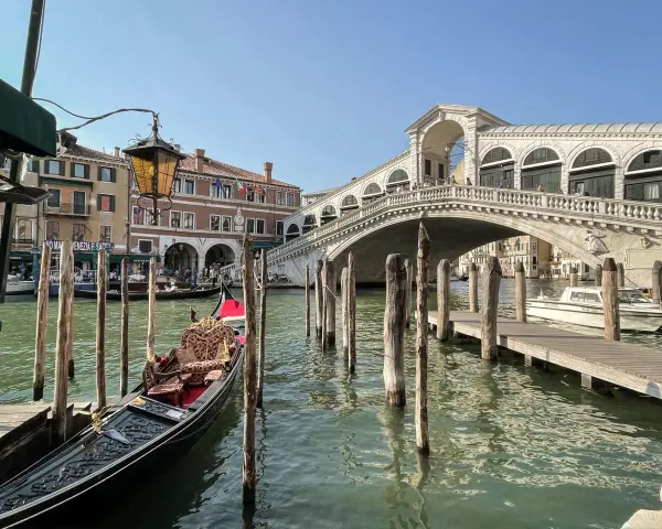Góndola esperando en el canal, con el Puente de Rialto al fondo. Ideas para que ver en Venecia en dos días.