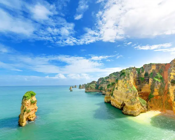 Acantilados dorados y mar turquesa. Un lugar idílico para saber donde viajar en agosto barato y disfrutar de la naturaleza.