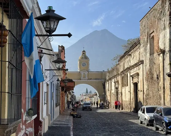 Calle empedrada en Antigua Guatemala, con el arco de Santa Catalina y el volcán de Agua al fondo. Ideal para descubrir qué ver en Antigua Guatemala.