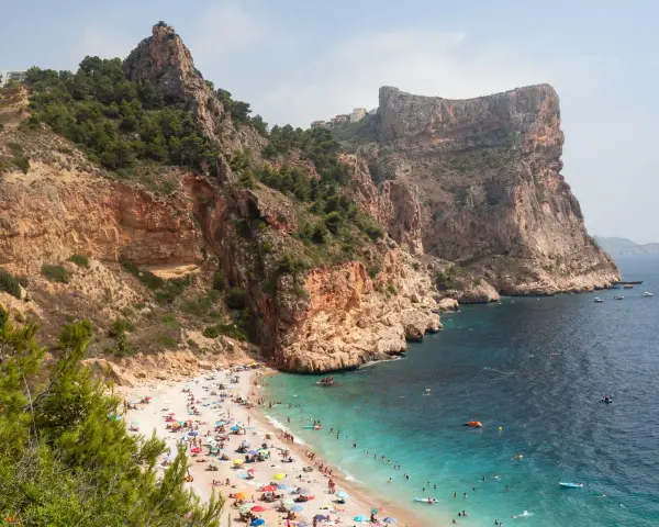 Playa con acantilados y gente disfrutando del sol y el mar. Un plan perfecto para saber qué ver en Alicante provincia en una semana.