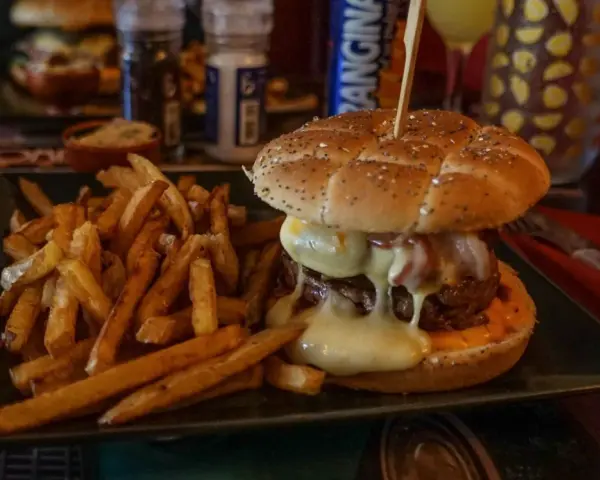 Jugosa hamburguesa con queso fundido y patatas fritas, ideal para saber donde comer en Carcassonne.