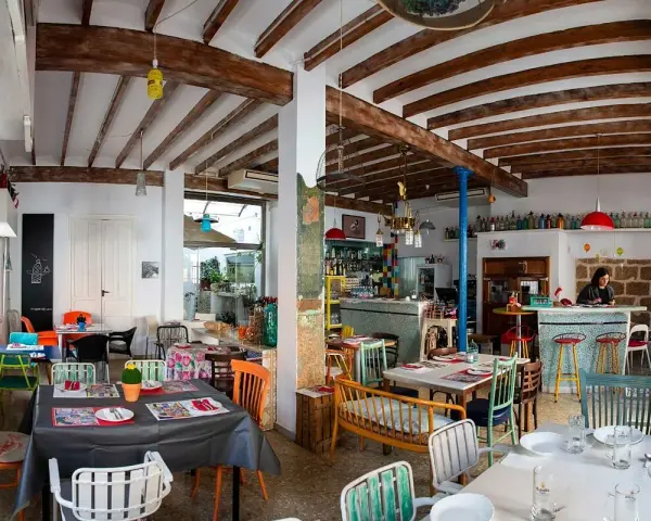 Un restaurante acogedor en Dénia, con mesas coloridas y vigas de madera. Ideal para saber donde comer en Dénia.