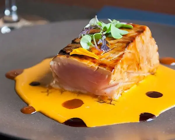 Un delicioso atún sellado sobre una cremosa salsa de naranja, perfecto para comer en Cambados.