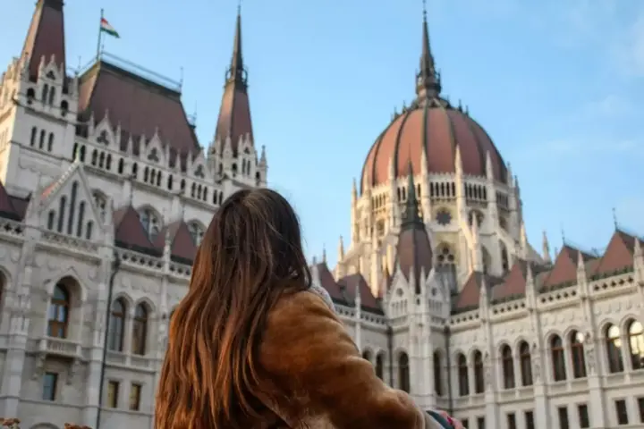 Mujer con abrigo de pelo admira el Parlamento de Budapest, un destino ideal donde viajar en noviembre en Europa.
