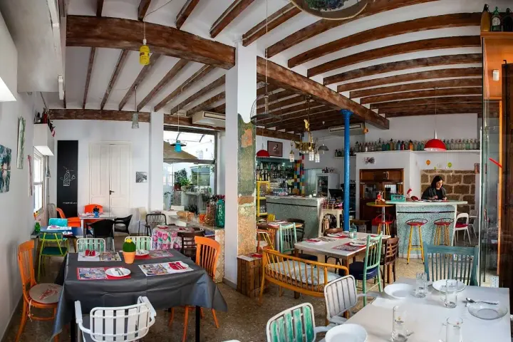 Un restaurante acogedor en Dénia, con mesas coloridas y vigas de madera. Ideal para saber donde comer en Dénia.