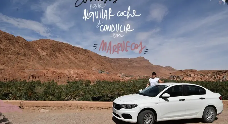 Consejos para alquilar coche y conducir en Marruecos. Paisaje desértico con palmeras y una mujer junto a un coche blanco.