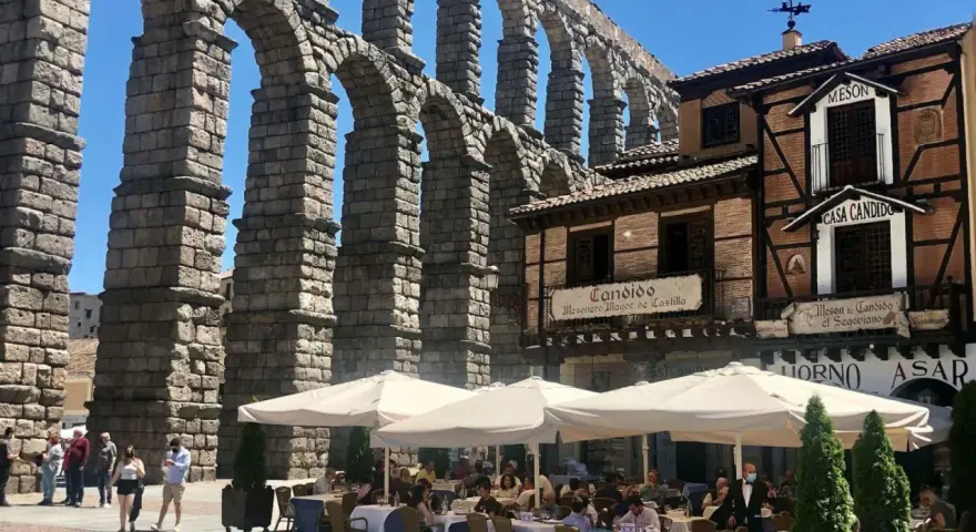 Mesón de Candido, un lugar ideal donde comer en Segovia, bajo el imponente acueducto. Mesas al aire libre.