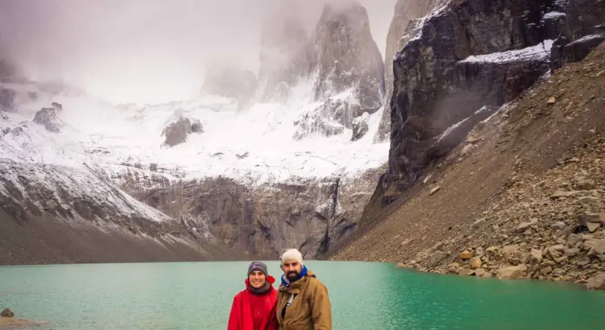 Pareja posa frente a un lago turquesa y montañas nevadas, un paisaje imperdible que ver en Chile.