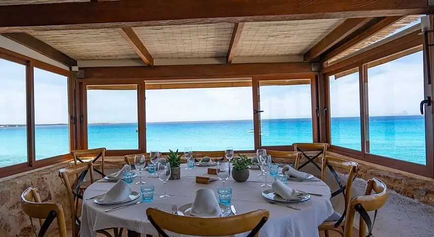 Mesa puesta con vistas al mar turquesa, ideal para saber donde comer en Formentera.