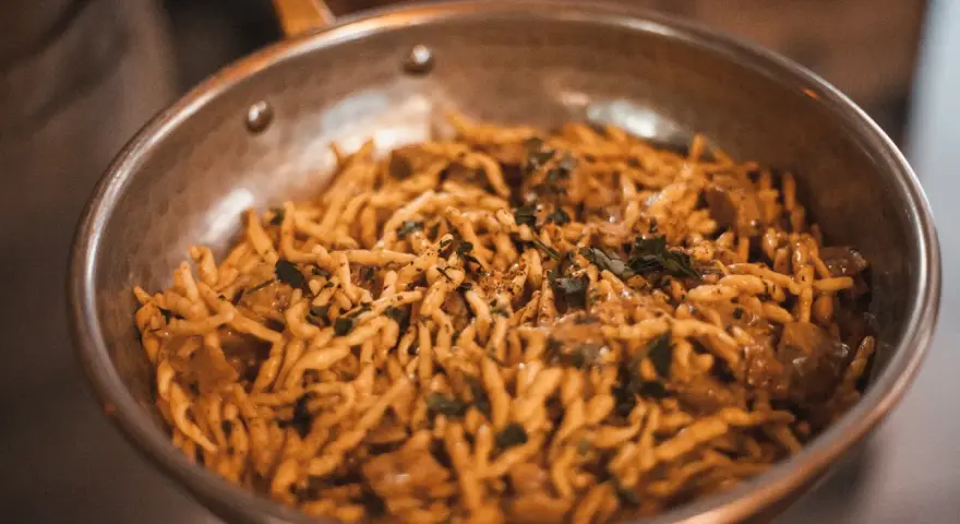 Pasta con salsa cremosa y hierbas en sartén. ¡Una deliciosa opción para saber dónde comer en Madrid!