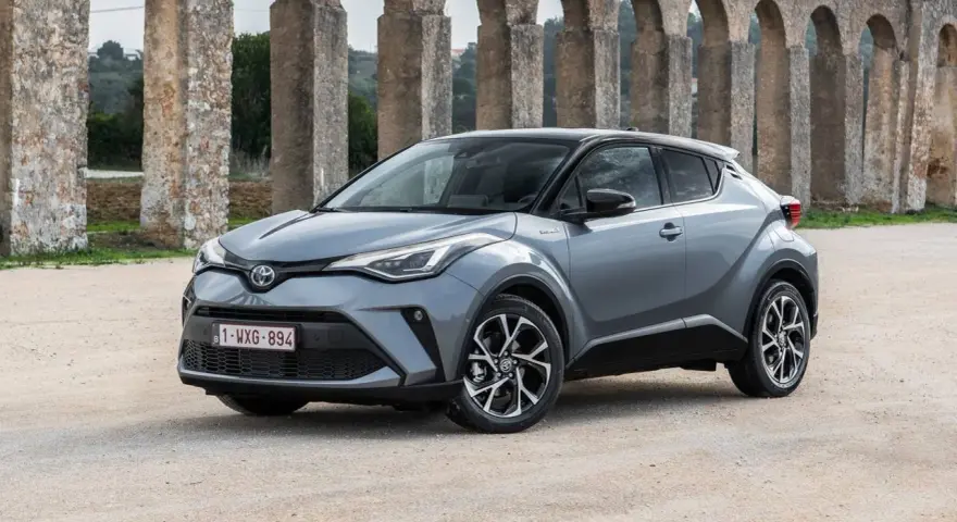 Toyota C-HR gris, un coche ideal para quienes buscan coches baratos de mantener, aparcado frente a un acueducto.