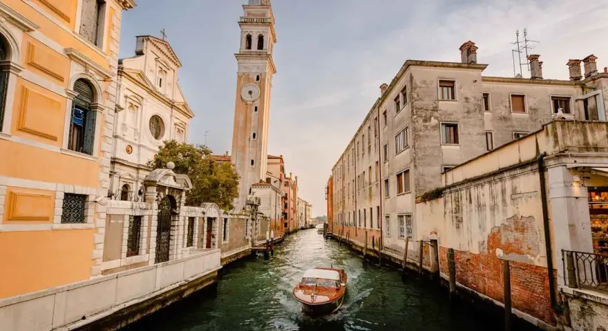 Un canal veneciano con un barco de madera y edificios antiguos. ¿Cuántos días para ver Venecia?