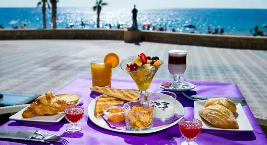 Desayuno frente al mar en Calpe: cruasanes, tostadas, fruta fresca, yogur y café. ¡Un lugar ideal donde comer en Calpe!