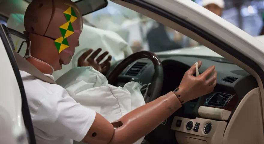 Maniquí en coche con cinturón de seguridad y airbag desplegado, demostrando seguridad pasiva y activa ejemplos.