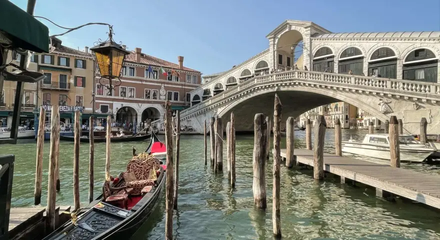 Góndola esperando en el canal, con el Puente de Rialto al fondo. Ideas para que ver en Venecia en dos días.