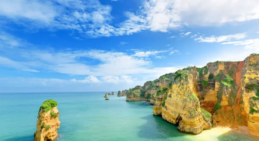 Acantilados dorados y mar turquesa. Un lugar idílico para saber donde viajar en agosto barato y disfrutar de la naturaleza.