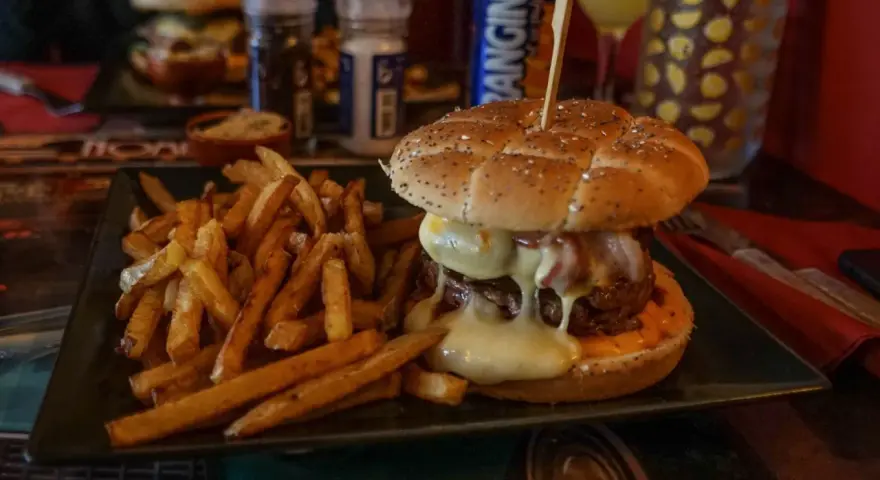 Jugosa hamburguesa con queso fundido y patatas fritas, ideal para saber donde comer en Carcassonne.