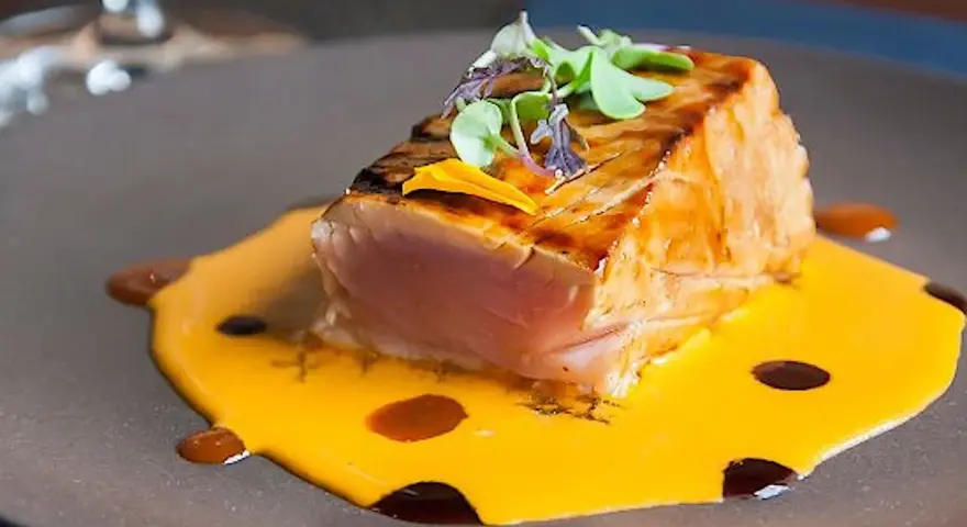 Un delicioso atún sellado sobre una cremosa salsa de naranja, perfecto para comer en Cambados.
