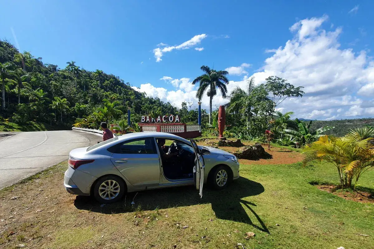 Un coche plateado aparcado junto a un cartel de 