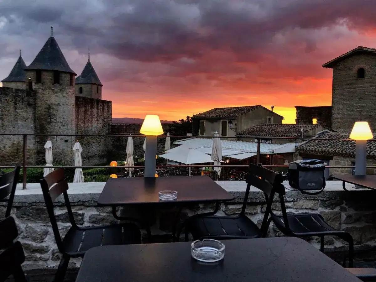 Atardecer espectacular sobre la ciudadela. Mesas listas para cenar, una opción ideal para saber donde comer en Carcassonne.