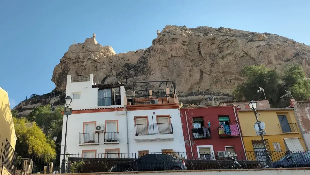 Edificios coloridos bajo el imponente Castillo de Santa B&aacute;rbara. &iexcl;Una vista perfecta que ver en Alicante en un d&iacute;a!