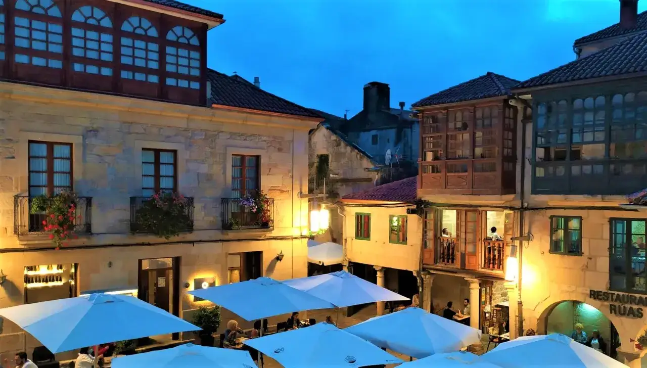 Plaza con terrazas iluminadas y balcones de madera. Un lugar perfecto para saber d&oacute;nde comer en Pontevedra.