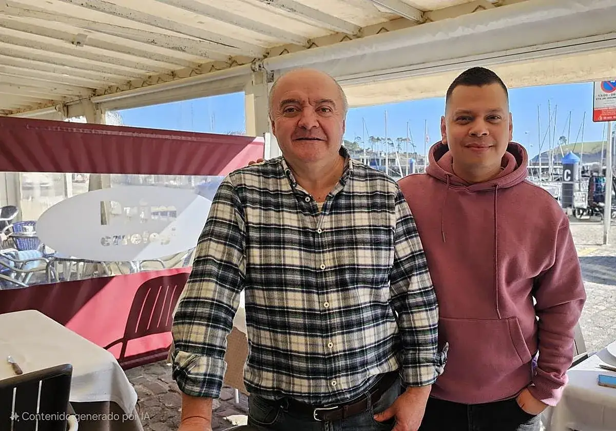 Dos hombres sonr&iacute;en en un restaurante con vistas al puerto de Lekeitio. &iexcl;Listos para comer!