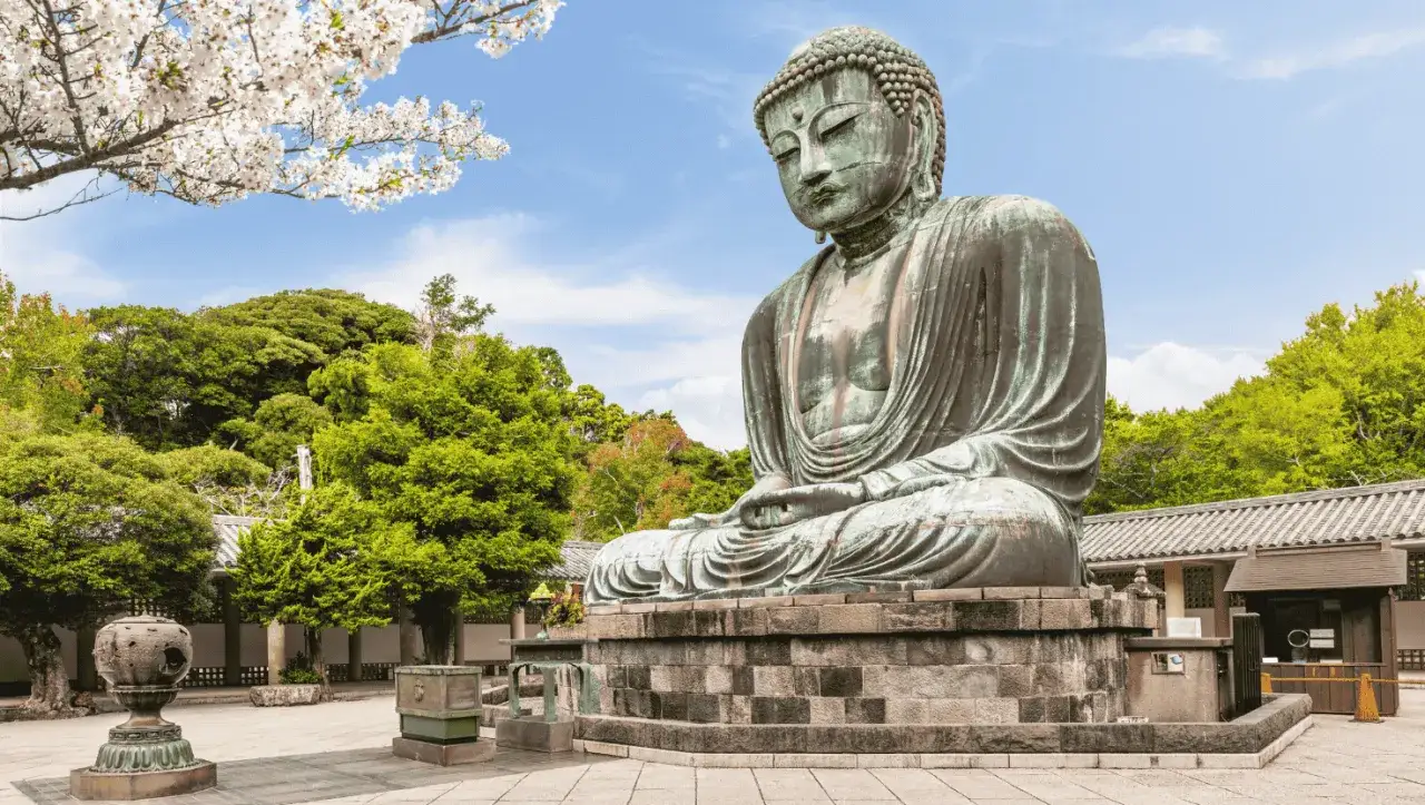 El Gran Buda de bronce, una maravilla que ver en Kamakura, sentado serenamente bajo cerezos en flor y rodeado de exuberante vegetaci&oacute;n.