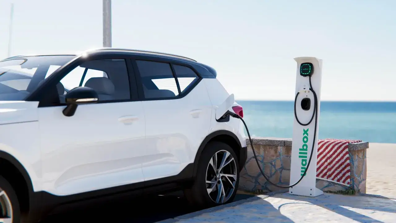 Coche blanco cargando en la costa, listo para seguir su viaje con coches cero emisiones.