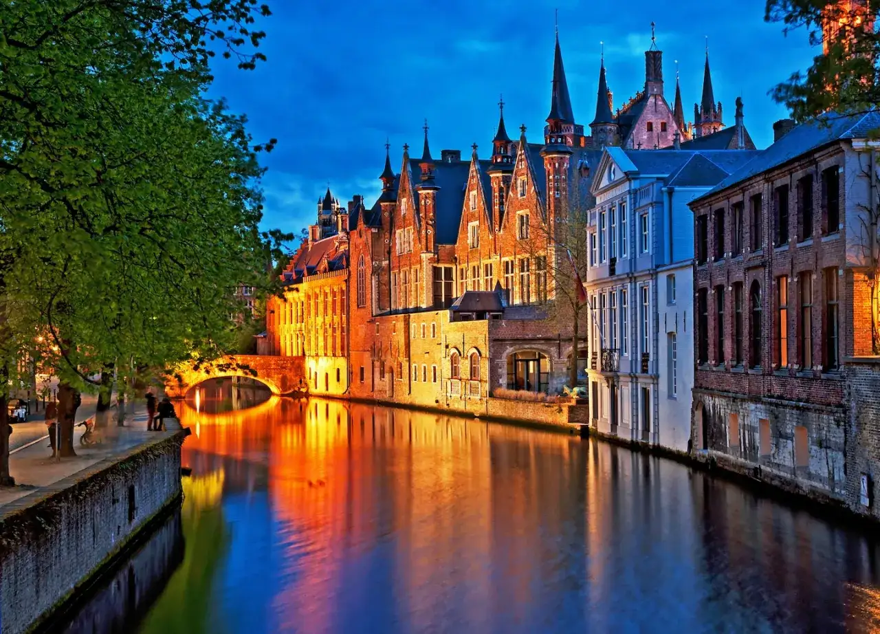 Canal iluminado con reflejos dorados y azules, edificios históricos y un puente. Ideal para saber donde viajar en noviembre en Europa.