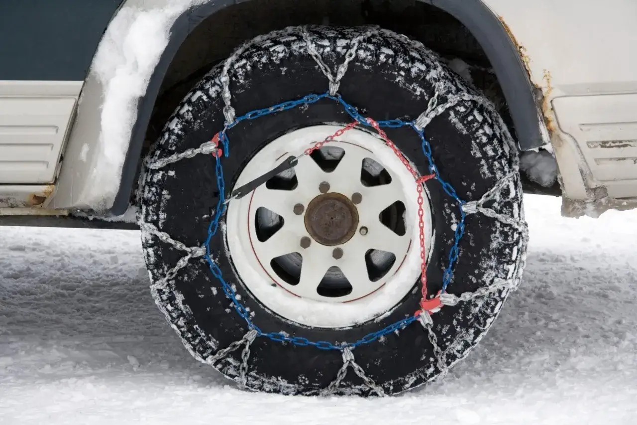Neumático con cadenas para la nieve, evitando una multa por no llevarlas.