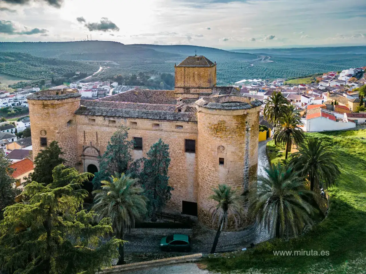 Castillo de Ba&ntilde;os de la Encina, un lugar imprescindible que ver en Ja&eacute;n. Palmeras y olivos rodean esta fortaleza hist&oacute;rica.