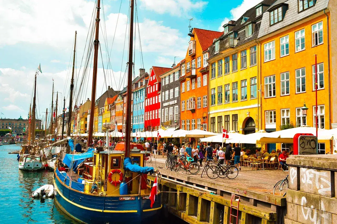 Coloridas casas junto a barcos en un canal. Un lugar vibrante que ver en Dinamarca, perfecto para pasear y disfrutar.