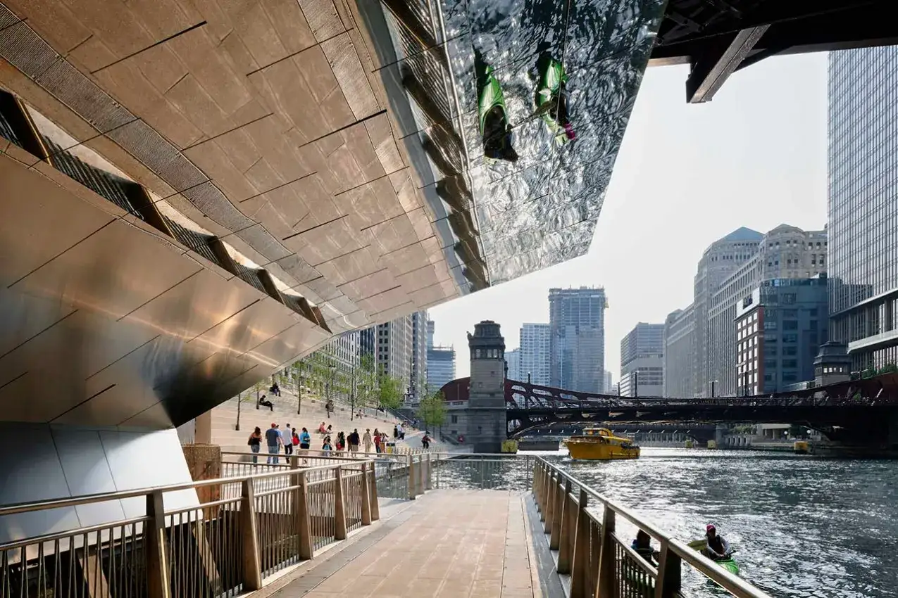 Paseo por el r&iacute;o Chicago, ideal para saber qu&eacute; ver en Chicago en 3 d&iacute;as. Gente pasea, un bote amarillo navega y se aprecian edificios ic&oacute;nicos.
