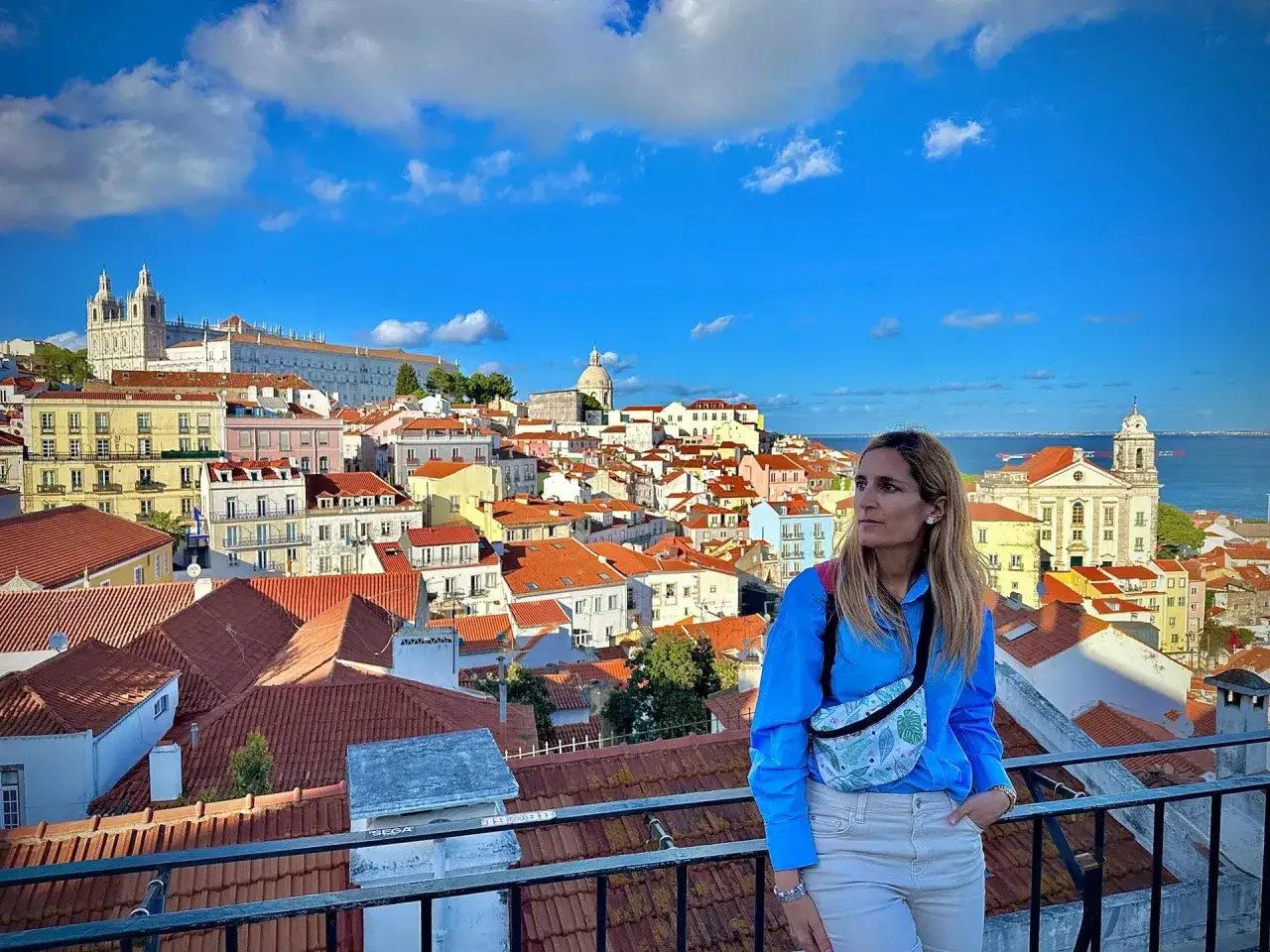 Mujer con bolsa cruzada admira el paisaje urbano de Lisboa, ideal para saber qu&eacute; ver en Lisboa en 3 d&iacute;as.