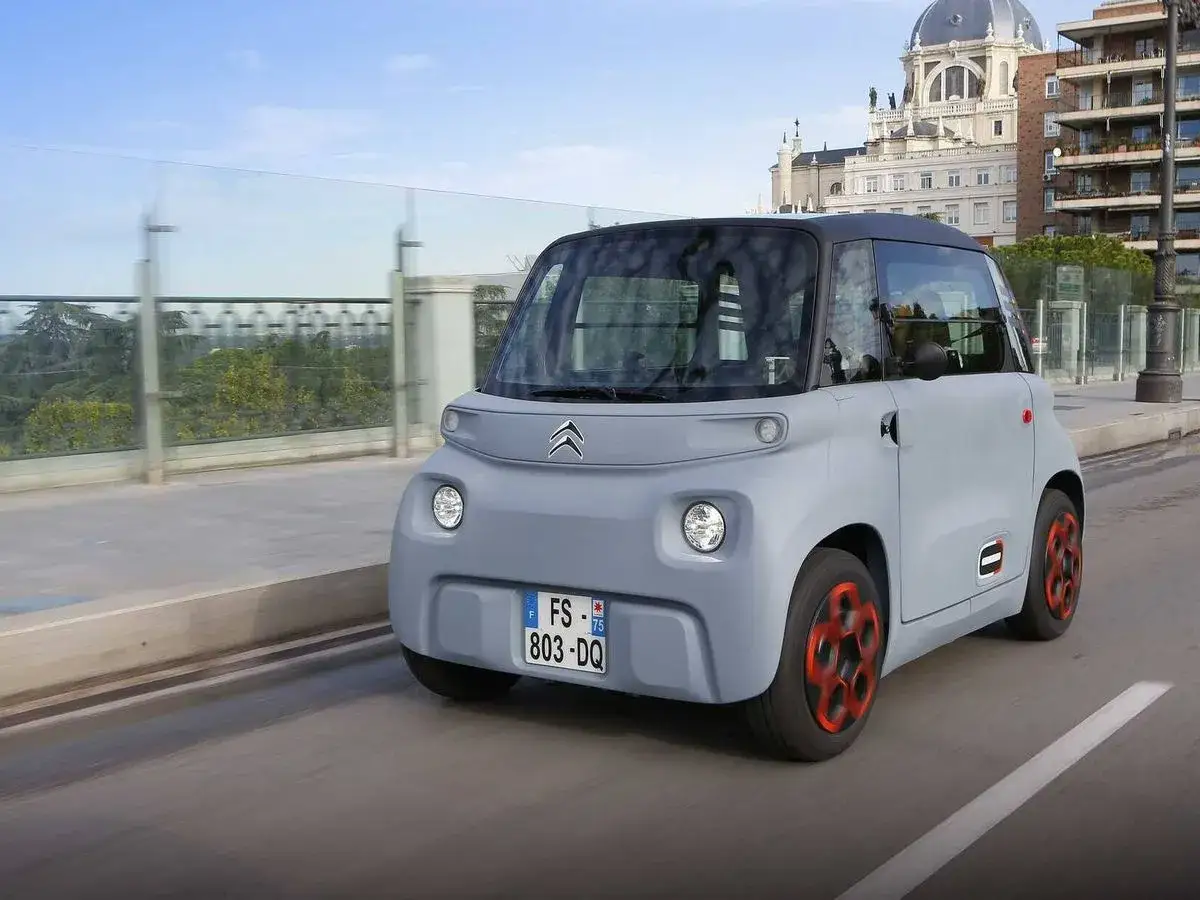 Coche el&eacute;ctrico gris con detalles naranjas circulando por Madrid. Descubre las ventajas coche el&eacute;ctrico Madrid y disfruta de la ciudad.