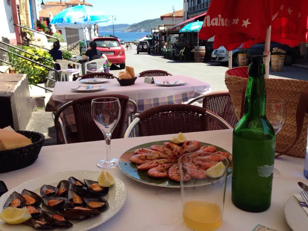 Una mesa lista para comer en tazones, con mejillones y gambas, en un d&iacute;a soleado junto al mar.